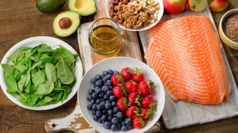 A selection of the best foods for type 2 diabetes, including leafy greens, fresh berries, salmon, avocado, olive oil, nuts, and flaxseeds, displayed on a wooden table for a balanced, nutritious meal.