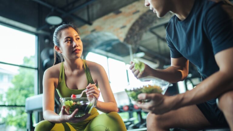 Dietitian tips for active lifestyle shown as a dietitian advising an active woman on healthy eating, with both holding fresh salads in a gym setting.