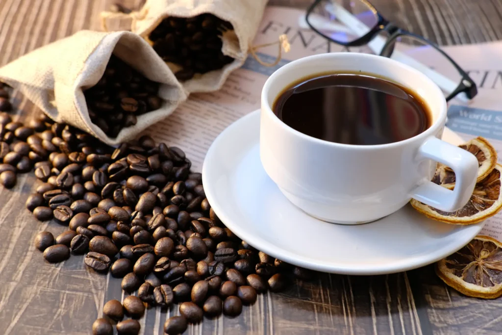 Cup of black coffee surrounded by roasted coffee beans, a caffeine source often discussed alongside evidence-based supplements