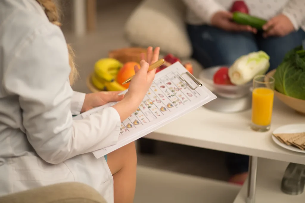Dietitian for anti-inflammatory diet reviewing a food chart on a clipboard with a client, with fresh fruit and juice on the table
